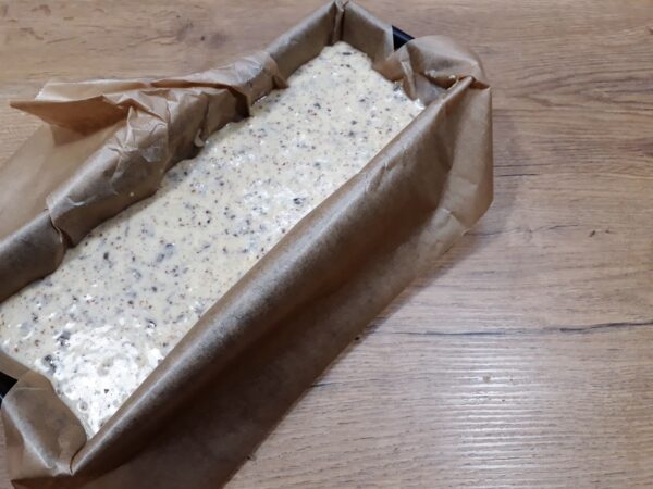 Eine mit Backpapier ausgelegte Kastenform, befüllt mit der Bananen-Nuss-Schokokuchen Teigmasse.