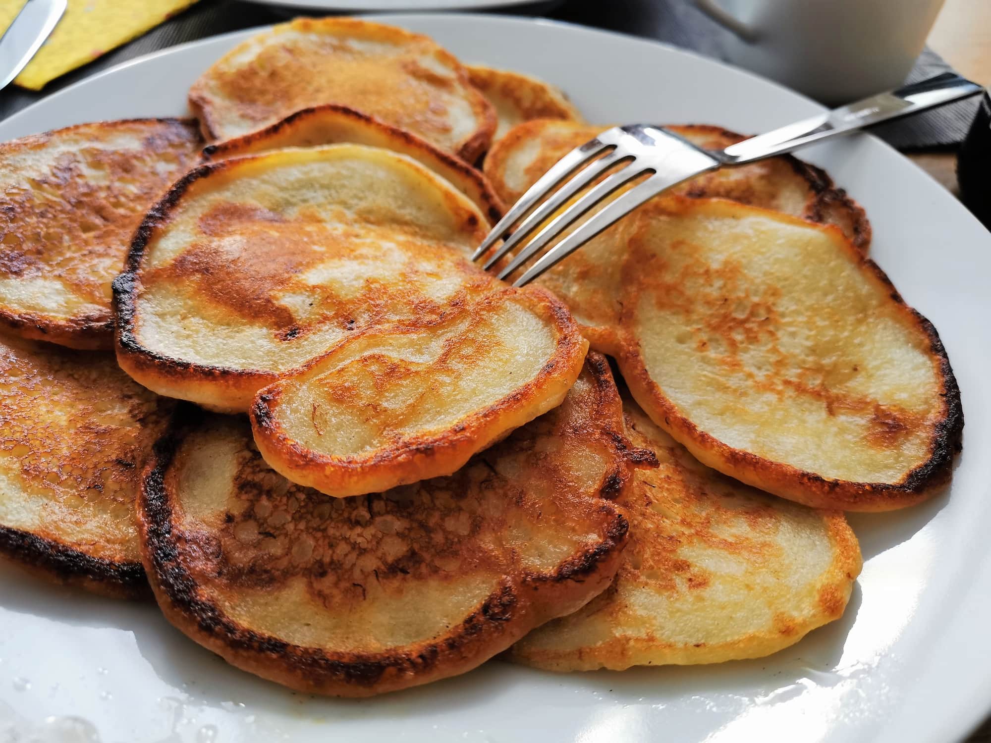 Ein Stapel Bananenpancakes serviert auf einem weißen Teller mit einer Gabel.