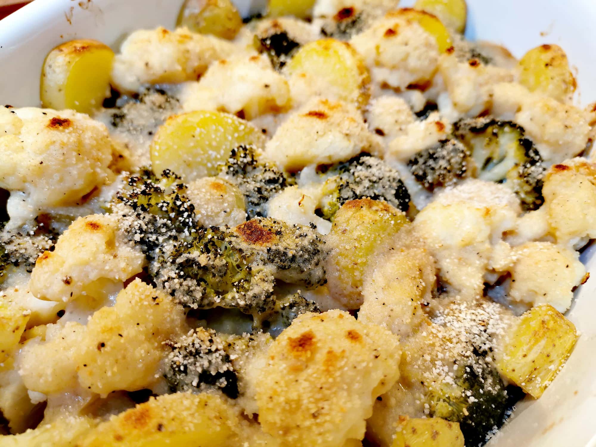 Gratin vom Karfiol und Brokkoli mit Erdäpfeln frisch aus dem Ofen in einer weißen Auflaufform.