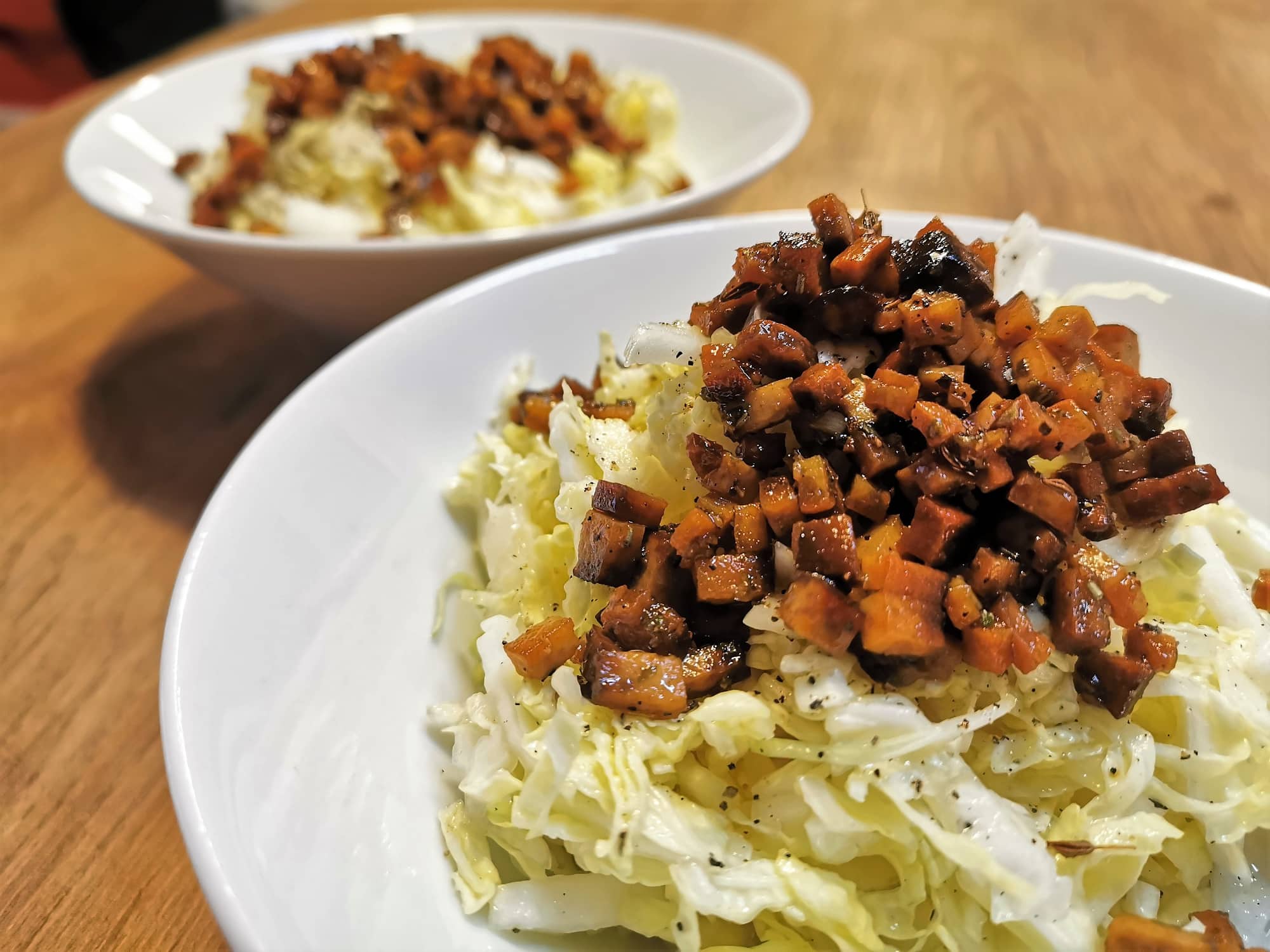 Jägersalat mit Tofuspeckwürferl bestreut angerichtet in weißen Salatschalen.