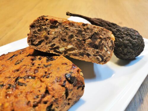 Kletzenbrot im Anschnitt garniert mit einer Dörrbirne (Kletze), angerichtet auf einem weißen Servierteller.