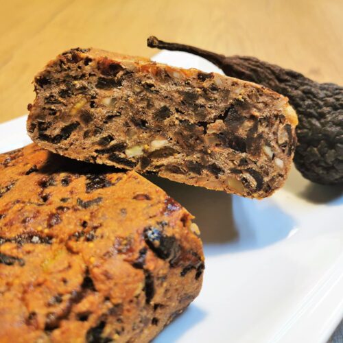 Kletzenbrot im Anschnitt garniert mit einer Dörrbirne (Kletze), angerichtet auf einem weißen Servierteller.