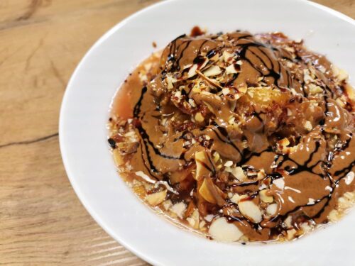 Overnight Chia-Oats mit Vanille-Nektarinen serviert in einem weißen Teller, getoppt mit Dattelsirup und braunem Mandelmus.