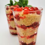 Gepoppte Hirse mit Kokos und Joghurt, abwechselnd mit Himbeeren in ein Glas geschichtet und mit Minze garniert.