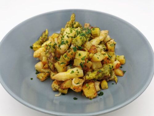 Spargel-Erdäpfel-Gröstl mit weißem und grünem Spargel und Kräutern, serviert in einem graublauen Suppenteller.