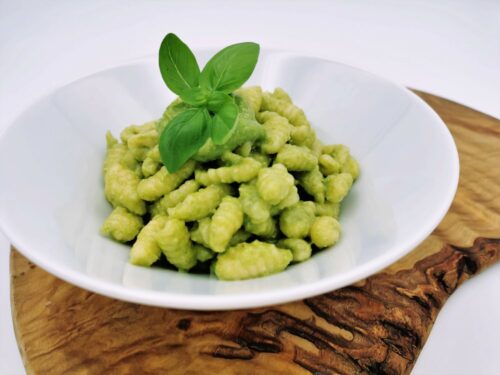 Selbstgemachte Gnocchettipasta mit Basilikumpesto, serviert in einem weißen Teller, garniert mit frischem Basilikum