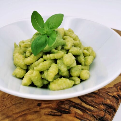 Selbstgemachte Gnocchettipasta mit Basilikumpesto, serviert in einem weißen Teller, garniert mit frischem Basilikum