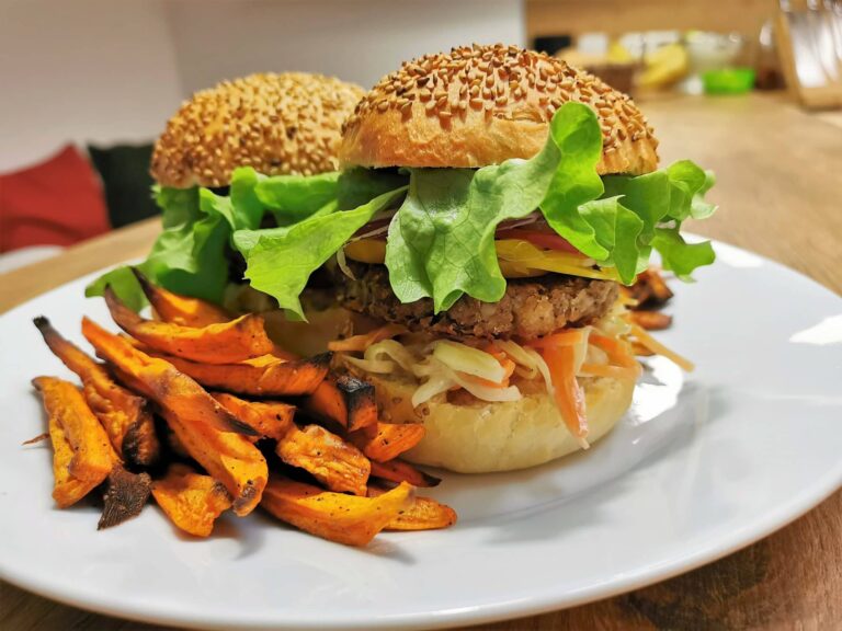 Zwei Burger mit Süßkartoffelpommes angerichtet auf einem weißen Teller